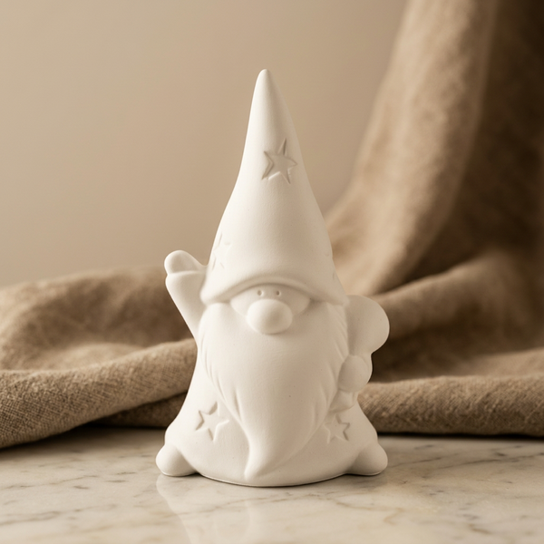 Anão branco de cerâmica perfumada, com barba alongada e braço erguido, sobre mármore junto a tecido bege.