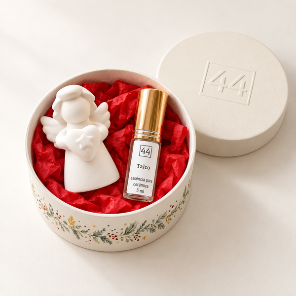 Mini Coffret Anjo em caixa redonda aberta, com anjo branco e essência de talco, sobre fundo claro.