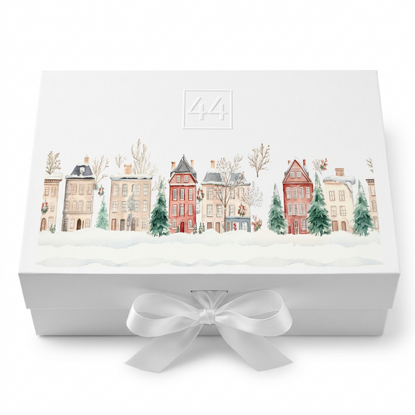Caixa de oferta da 44 com ilustração de casas natalícias e laço branco, sobre fundo claro.