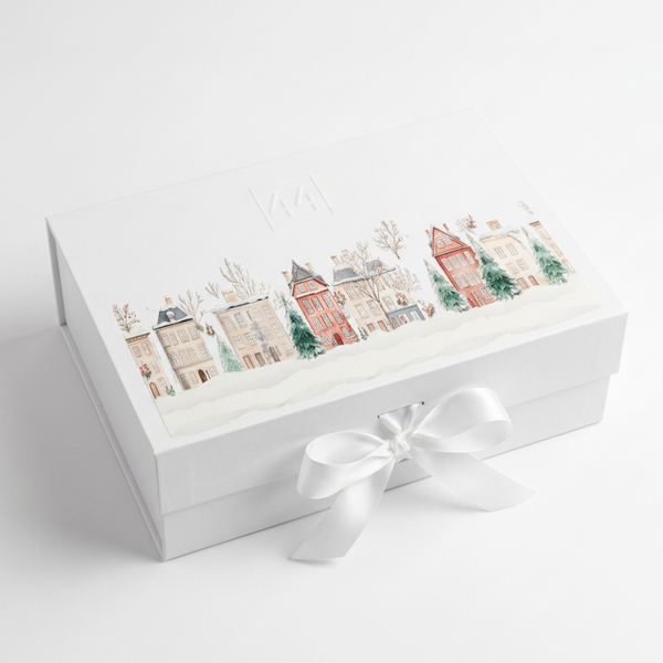 Caixa de oferta da 44 com ilustração de casas natalícias e laço branco, sobre fundo claro.
