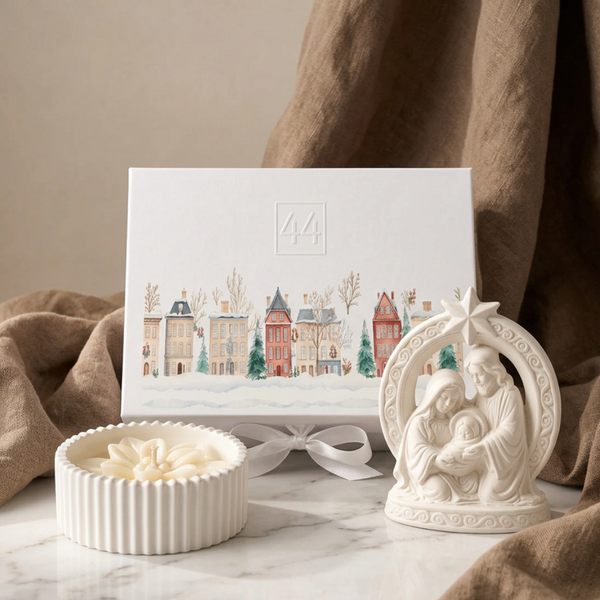 Coffret Presépio com vela decorada com Estrela de Natal em cera e caixa de oferta, junto a tecido bege.