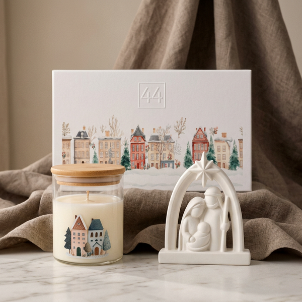 Vela aromática em vidro com tampa de bambu e presépio branco diante da caixa de oferta, junto a tecido bege.