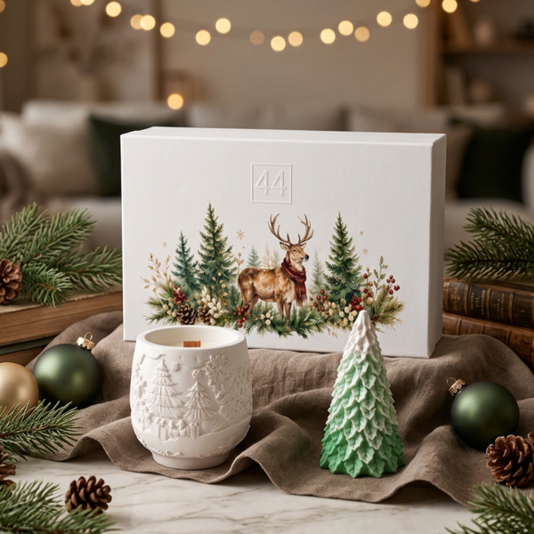 Coffret Pinheiro da 44, com vela em pote de cerâmica branca, pinheiro verde e caixa com ilustração de veados, em ambiente natalício.