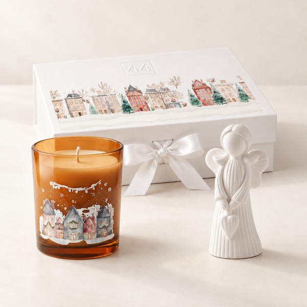 Coffret Âmbar com vela aromática, anjo branco e caixa de oferta com laço, sobre fundo claro.