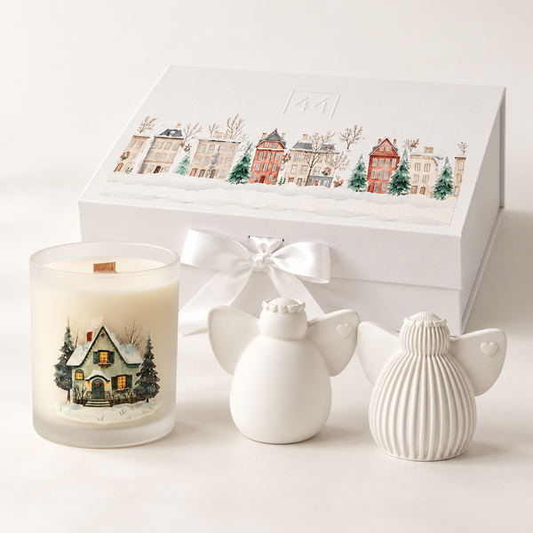 Coffret Anjos com vela aromática, duas figuras de cerâmica branca e caixa natalícia com laço, sobre fundo claro.