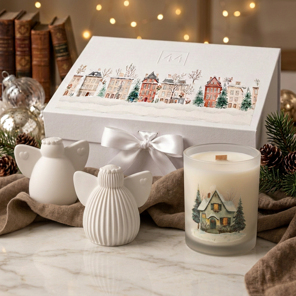 Coffret Anjos da 44, com dois anjos brancos de cerâmica perfumada, vela natalícia e caixa com laço, em ambiente de Natal.
