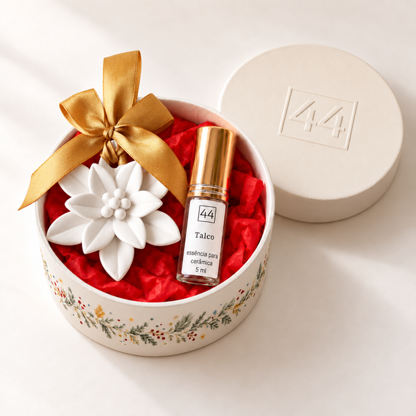 Mini Coffret Flor em caixa redonda aberta, com Estrela de Natal de laço dourado e essência de talco, sobre fundo claro.