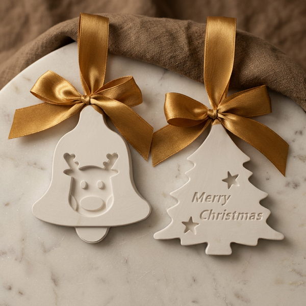 Sino com rena e pinheiro com inscrição Merry Christmas, em cerâmica branca com laços dourados, sobre mármore.