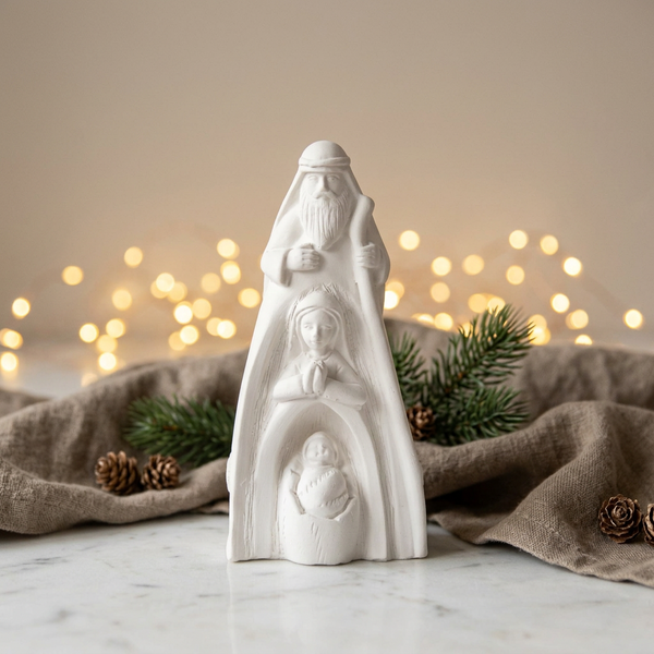 Sagrada Família Alta de cerâmica perfumada branca, entre ramos verdes, pinhas e luzes de Natal.
