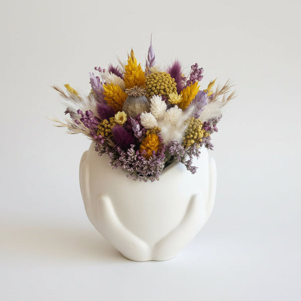 Vaso decorativo branco com mãos segurando coração e flores secas estilo minimalista e romântico.
