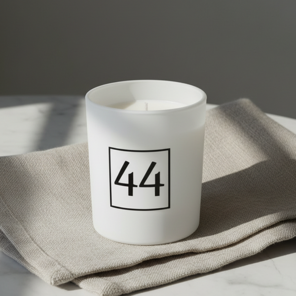 Vela aromática em copo branco fosco produzida artesanalmente com cera vegetal.