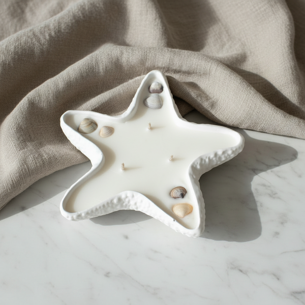 Vela aromática artesanal da Coleção Conchas de Luz em estrela do mar de cerâmica decorada com elementos marinhos.
