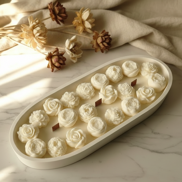 Vela artesanal em recipiente de cerâmica branca com formato oval e flores de cera vegetal.