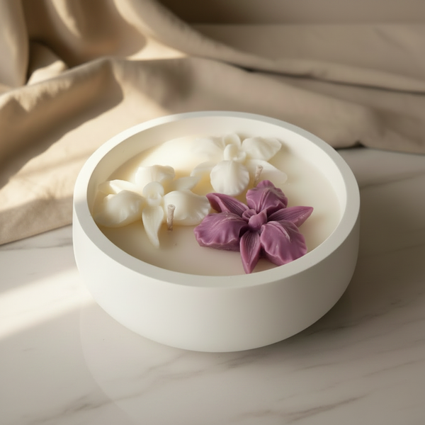 Vela artesanal em mini taça de cerâmica branca com flores de cera decorativas.