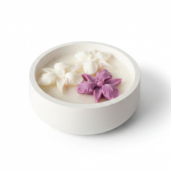 Vela artesanal em mini taça de cerâmica branca com flores de cera decorativas.