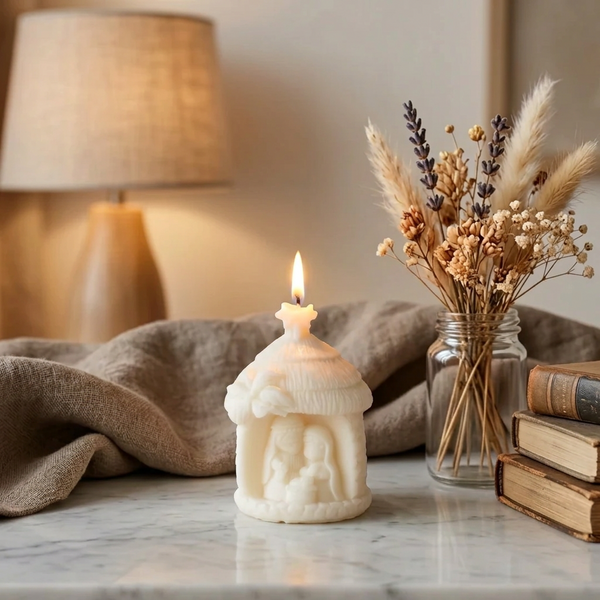 Vela decorativa Presépio acesa, junto a livros e flores secas numa sala em tons neutros.