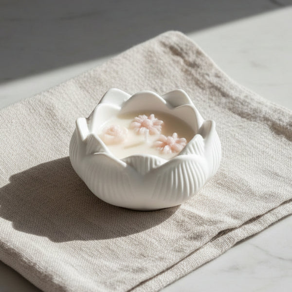 Vela artesanal em taça de cerâmica branca com formato de flor de lótus.